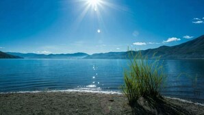 Un lac, un ciel dégagé, un soleil éclatant et des montagnes à l’horizon.