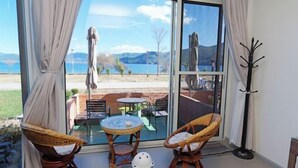 Une pièce dotée d’une porte vitrée donnant sur un patio extérieur, avec des chaises en osier, une petite table et un porte-manteau.