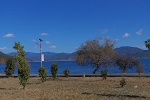 A clear view of a lake with mountains in the background, a few trees, and a clear sky. - Cuihu Bay Homestay (Lugu Lake Daluoshui Wharf) (Ninglang)