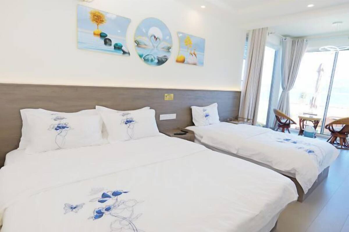 A hotel room with two beds, a dining area, and artwork on the wall.