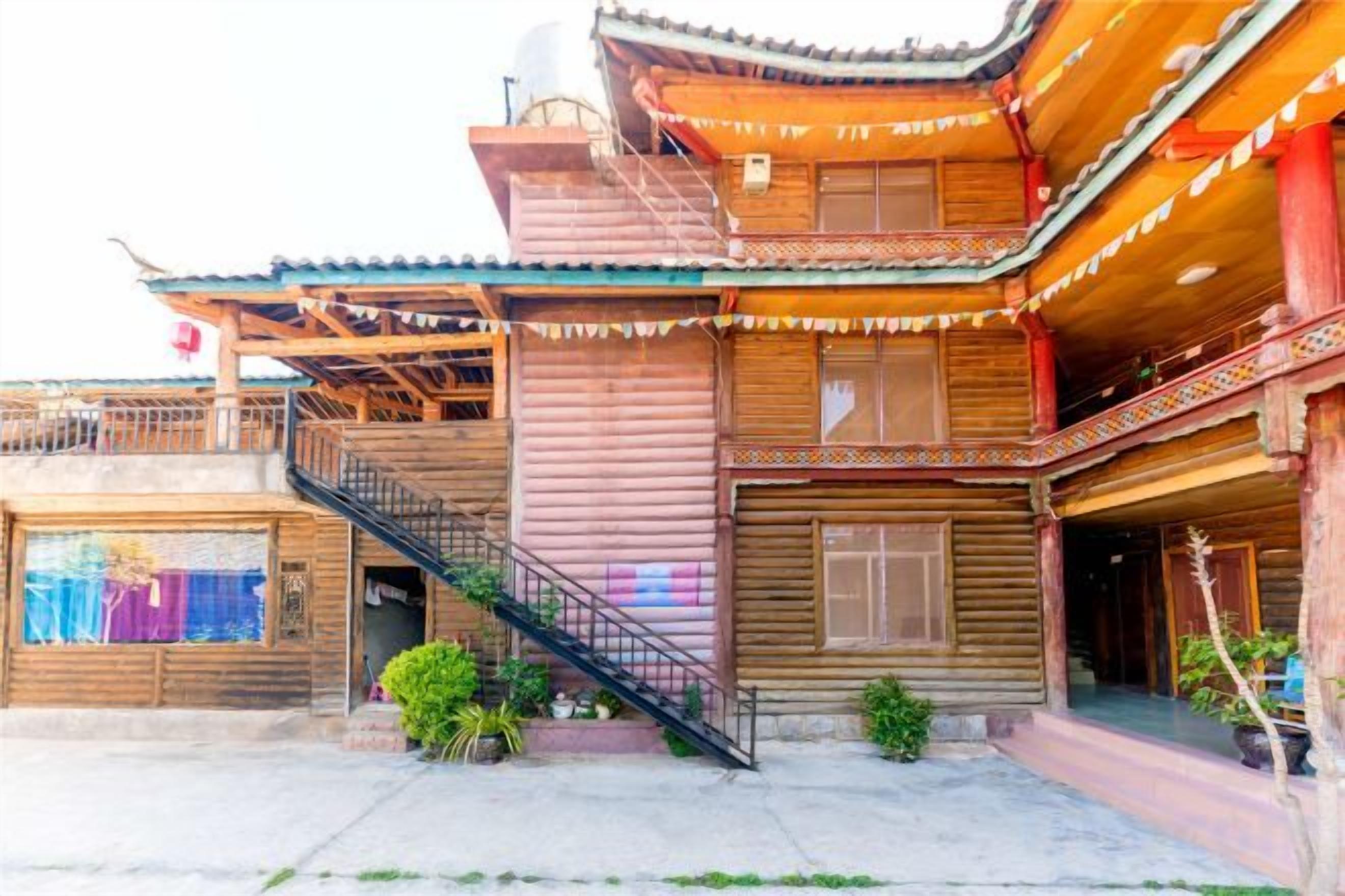 A traditional wooden building with a staircase, balconies, and a covered entrance.