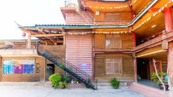 A traditional wooden building with a staircase, balconies, and a covered entrance.