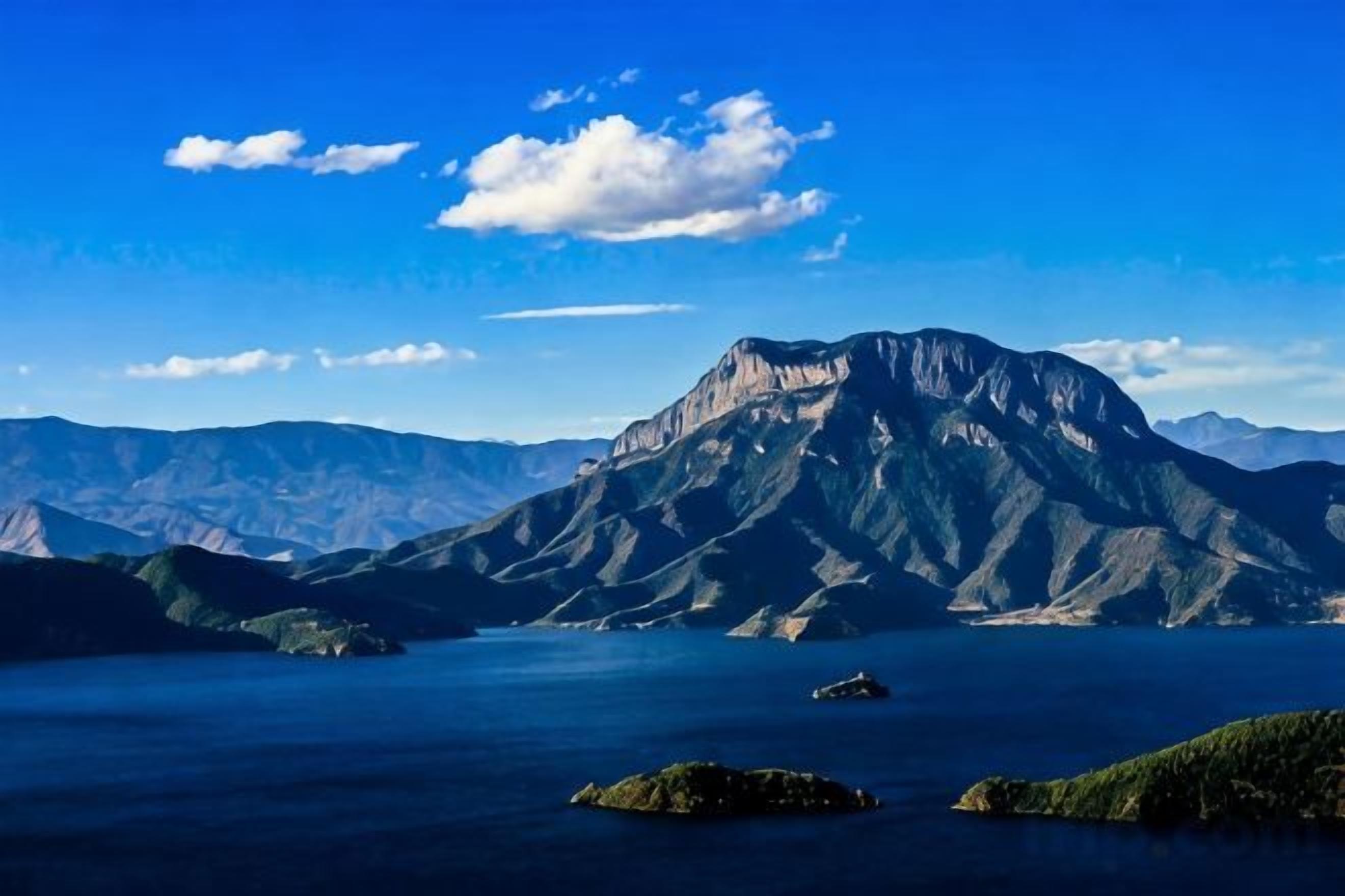 A mountain range with a lake in the foreground and a clear sky.