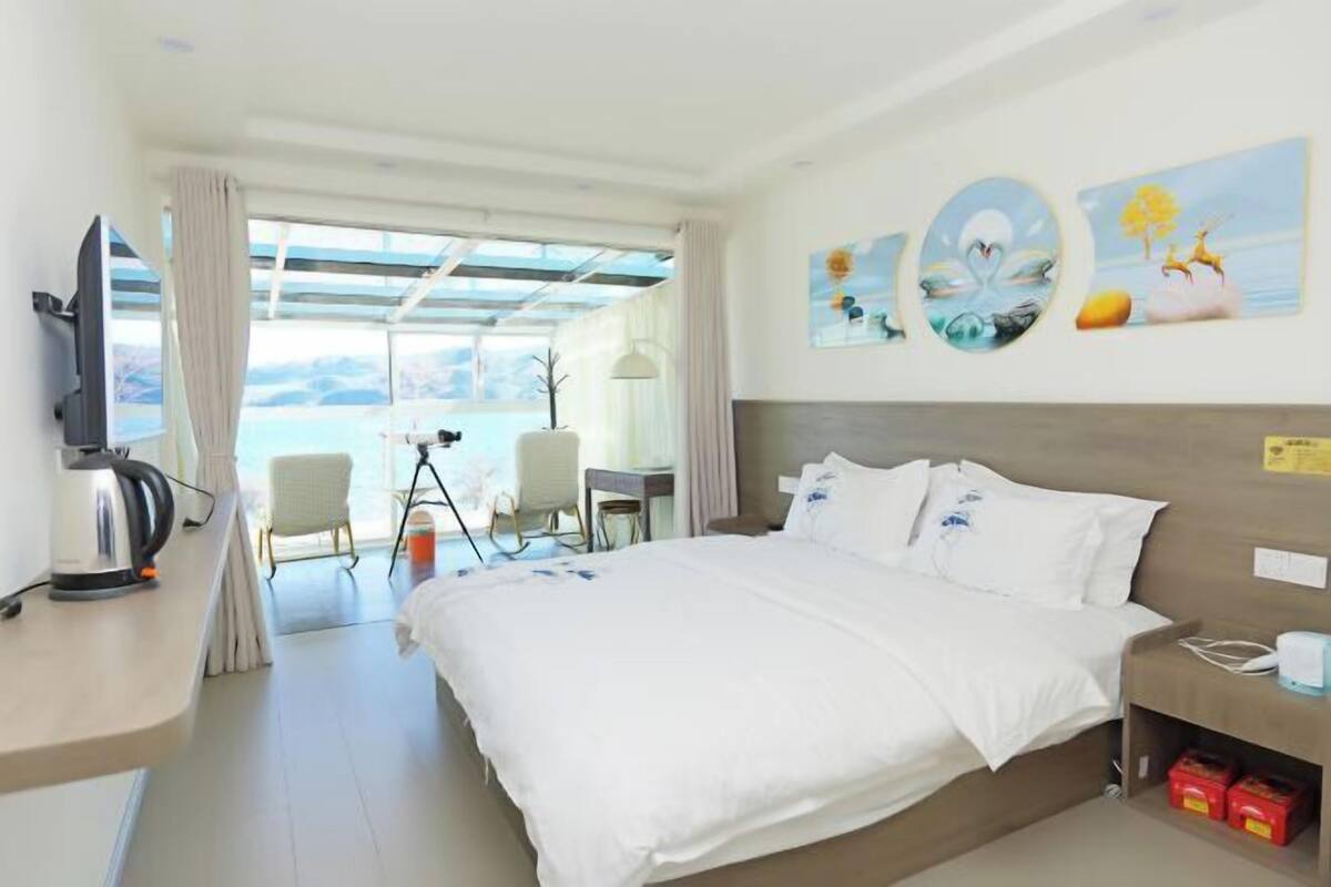 A hotel room with a bed, a desk, a chair, a television, and artwork on the wall.