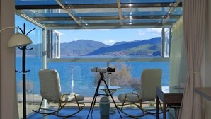 Une pièce dotée d’un plafond en verre, de deux fauteuils à bascule, d’un télescope et offrant une vue sur un lac et des montagnes.
