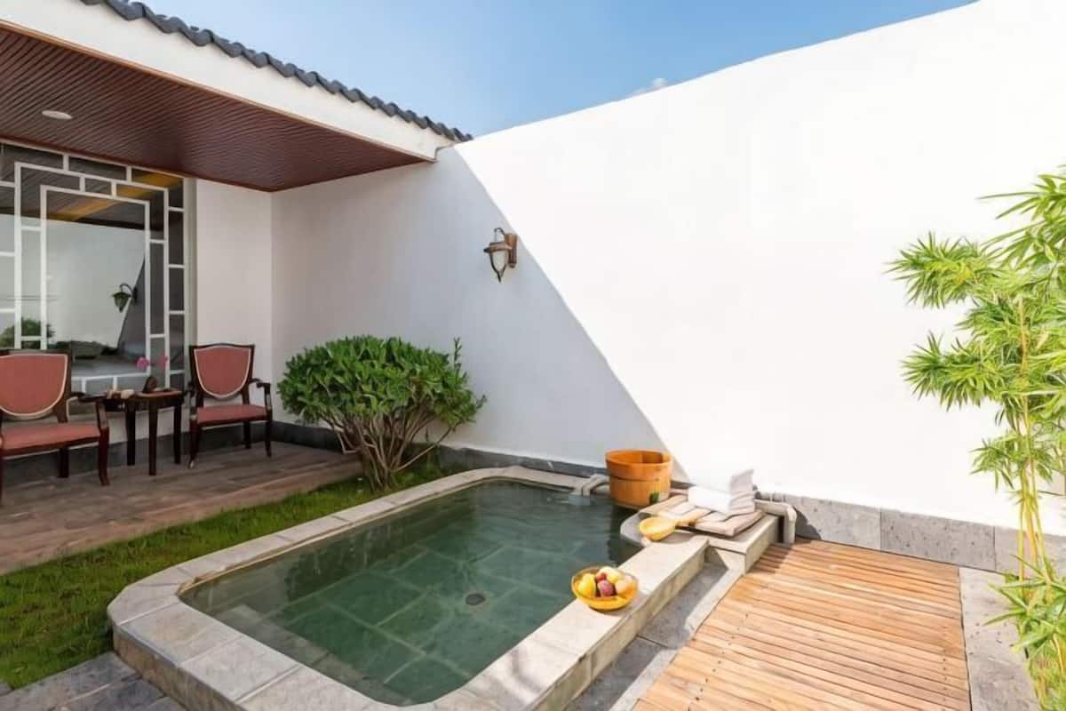 A spa area with a hot tub, wooden deck, and seating.