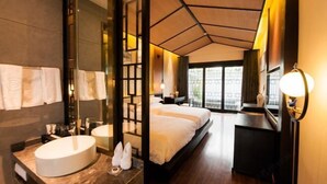 A modern hotel room with a large bed, a separate bathroom with a sink, and a view of the city through large windows. - Dali Geothermal Paradise Hotel (Eryuan)