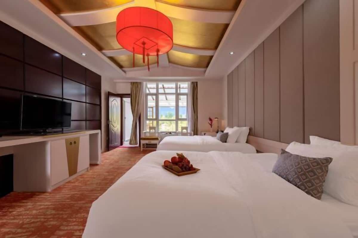 A hotel room with two beds, a TV, and a large window.