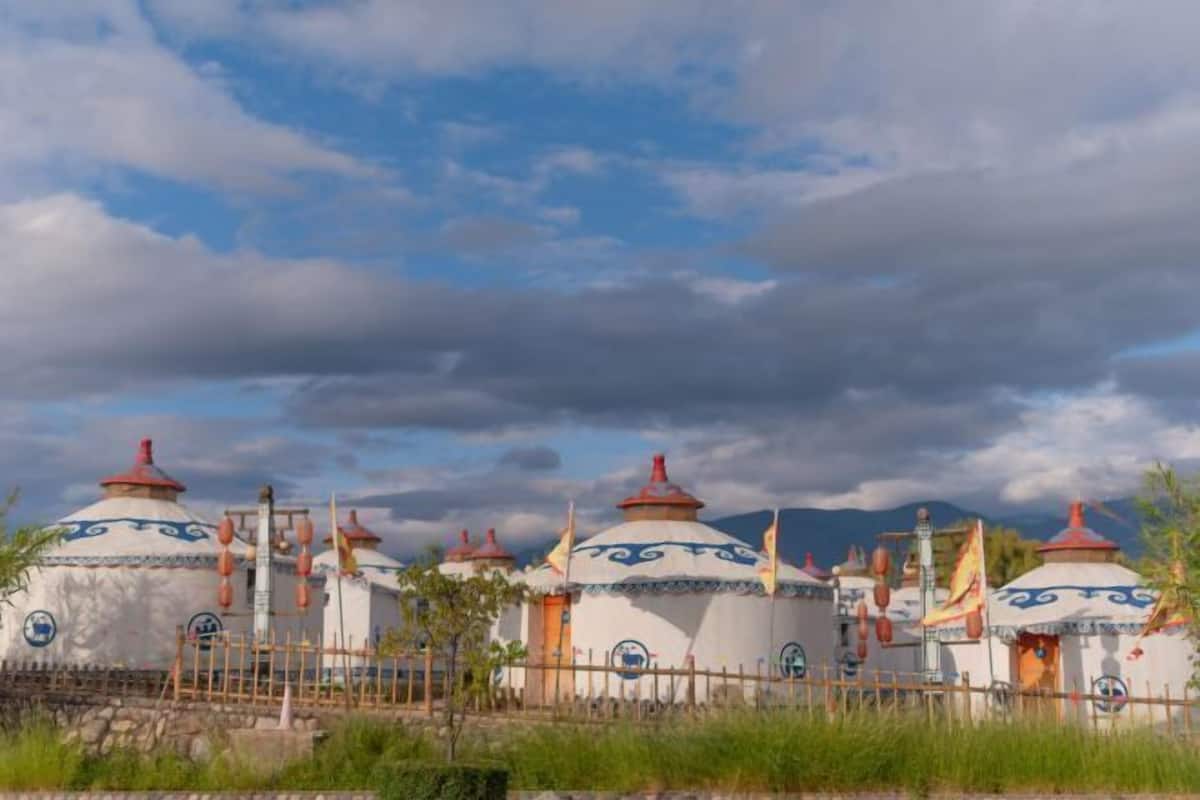 A row of traditional yurts with a stone wall in the foreground.