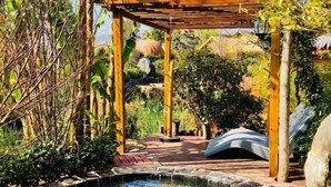 A wooden pergola with a small pool and a waterfall in the background. - Dali Geothermal Paradise Hotel (Eryuan)