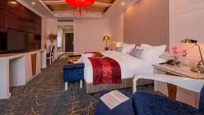 A hotel room with a bed, bedside table, chair, and a TV. - Dali Geothermal Paradise Hotel (Eryuan)