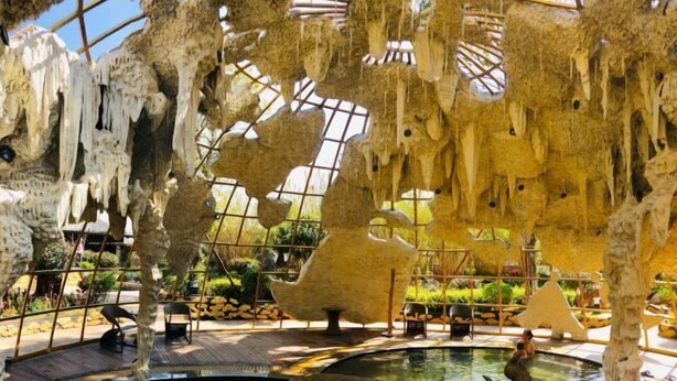 An indoor space with hanging stalactites, a central water feature, and a large sculptural installation. - Dali Geothermal Paradise Hotel (Eryuan)