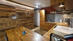 Una cocina moderna con paneles de madera, un comedor con mesa de madera y un horno empotrado.