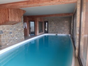 A swimming pool with stone walls and wooden beams. - Chalet des Jonquilles - Magnifique maison avec piscine (Les Angles)