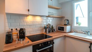 A modern kitchen with white cabinets, a wooden countertop, a built-in oven, a microwave, and a window with a view of the outside.