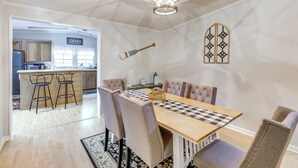 Un comedor con mesa de madera, mantel a cuadros y sillas acolchadas.