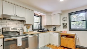 A modern kitchen with white cabinets, stainless steel appliances, and a wooden countertop.