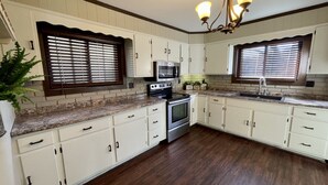 A kitchen with white cabinets, a granite countertop, a stove, an oven, a microwave, and a sink. - Historic Home within walking distance of Downtown Harmar & Marietta (Marietta)