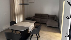A modern living room with a dining area, a sofa, and a table with chairs. - ROBI 2 Superior One-Bedroom Apartment with Terrace (veći) (Rovinj)