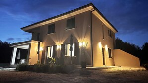 A modern two-story house with a garage, illuminated exterior lights, and a well-maintained lawn. - ROBI 2 Superior One-Bedroom Apartment with Terrace (veći) (Rovinj)