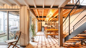 A modern interior with a wooden floor, a dining area, and a staircase. - Holiday Home 'Couleur Patio, Loft Atypique, Sauna' with Private Terrace, Balcony and Wi-Fi (Saint-Denis-d'Oléron)