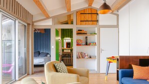 A modern living room with a sofa, armchair, and a dining table with chairs. - Holiday Home 'Couleur Patio, Loft Atypique, Sauna' with Private Terrace, Balcony and Wi-Fi (Saint-Denis-d'Oléron)