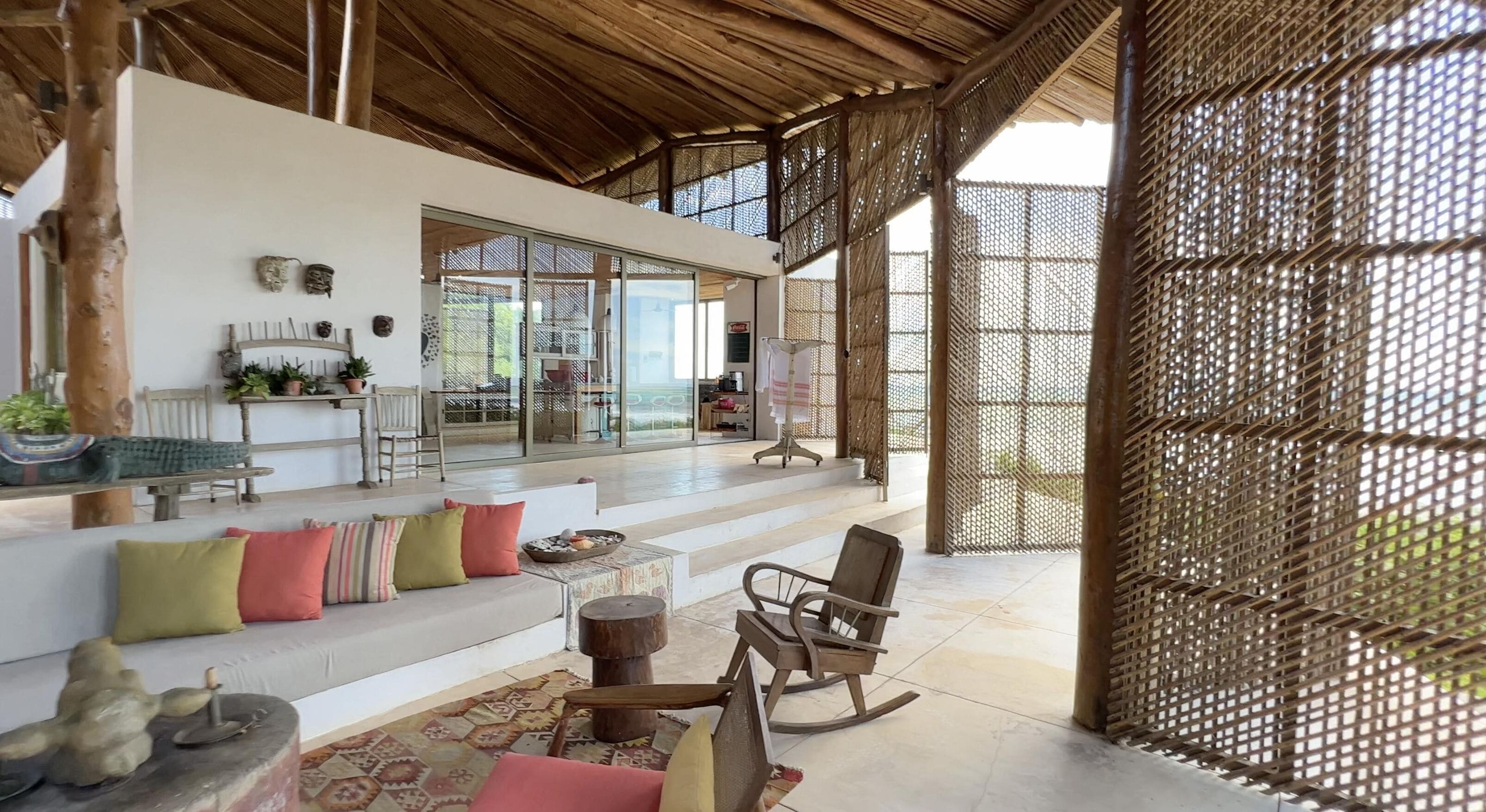 A spacious living area with a high ceiling, a sofa set, a rocking chair, and a dining table.