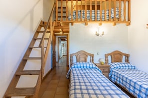 A bedroom with two beds, a wooden staircase, and a hallway leading to another room.