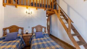 Un dormitorio con dos camas de madera, una mesita de noche, una lámpara y una escalera de madera.