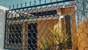 Una casa con facciata gialla, recinzione in metallo nero e una finestra con inferriata decorativa.