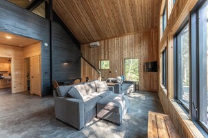 A modern interior with a sectional sofa, a dining area, and large windows.