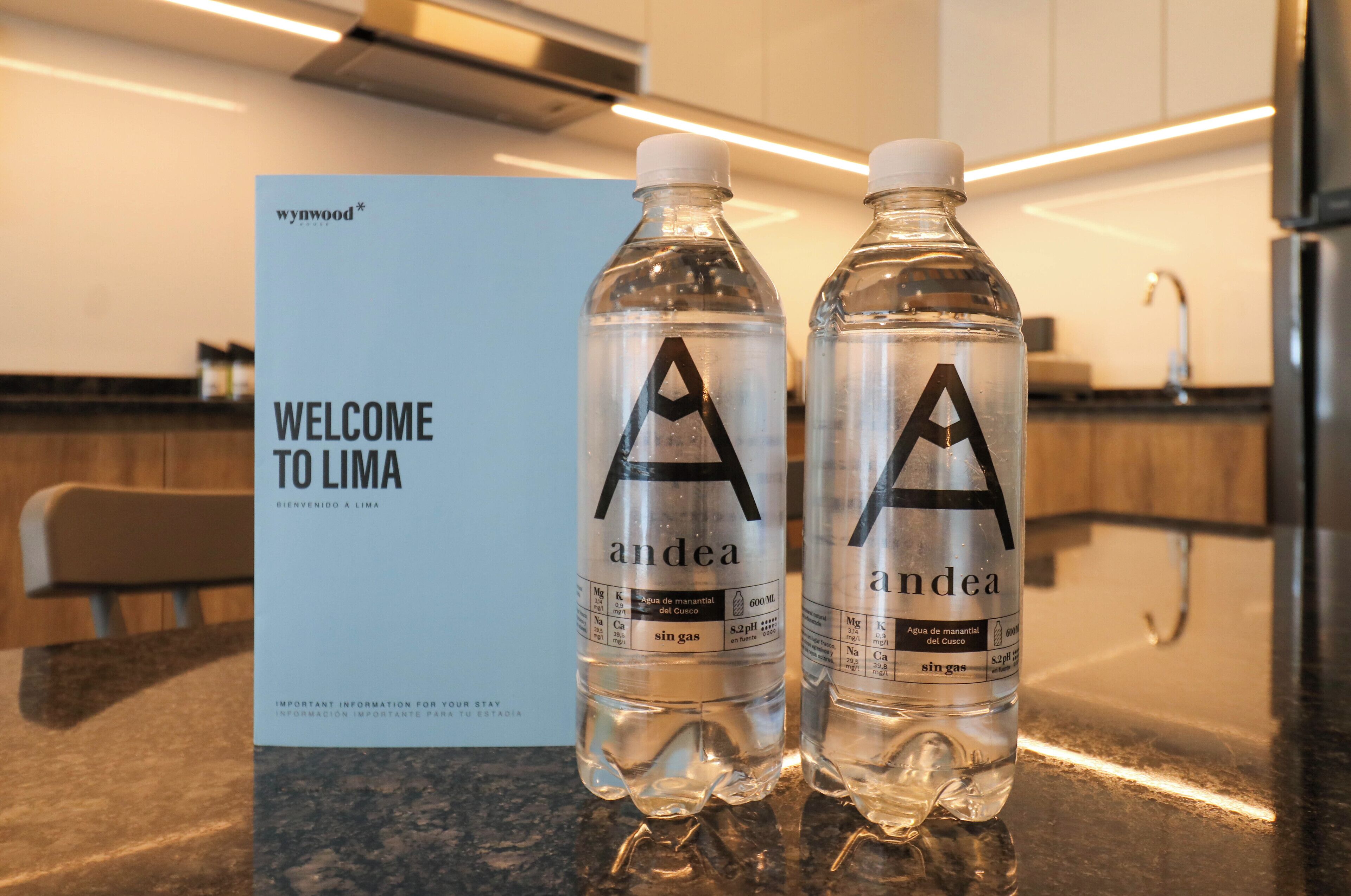Two bottles of water labeled 'andea' on a counter with a 'WELCOME TO LIMA' sign in the background.