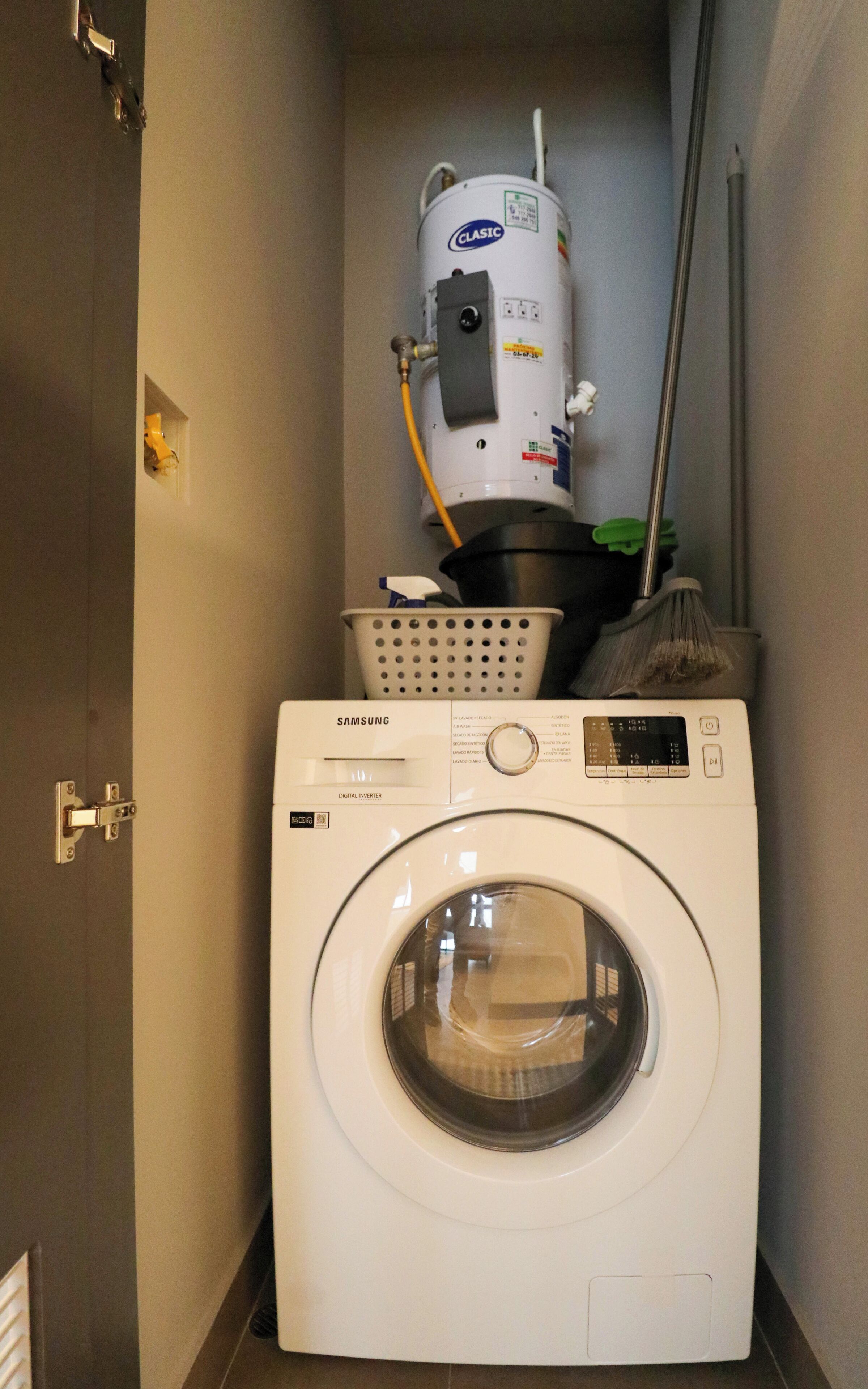 Un lavadero con una lavadora Samsung digital inverter y un calentador de agua.