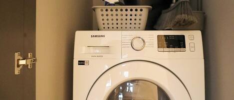 Un lavadero con una lavadora Samsung digital inverter y un calentador de agua.