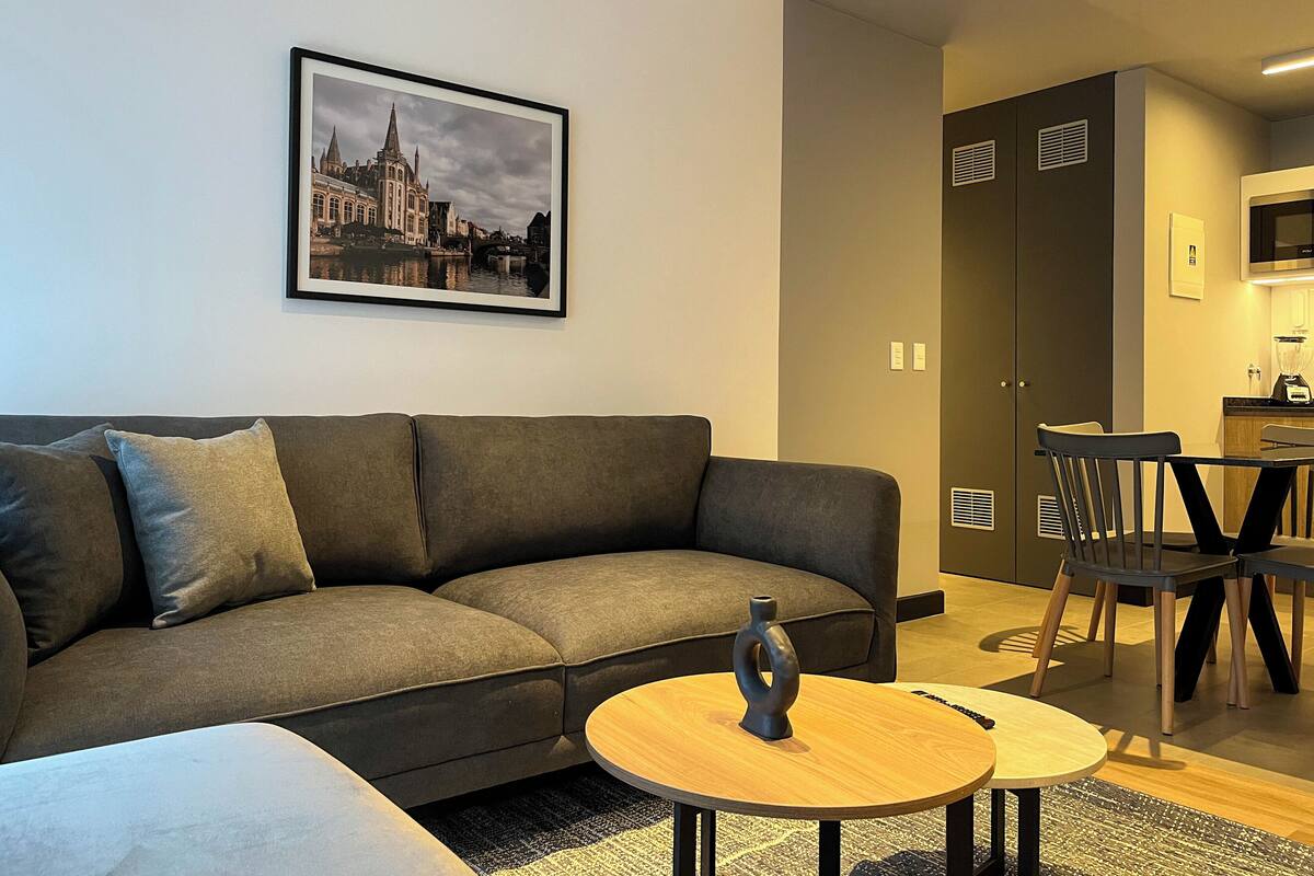 Ein modernes Wohnzimmer mit Sofa, Couchtisch und einem Essbereich mit Tisch und Stühlen.