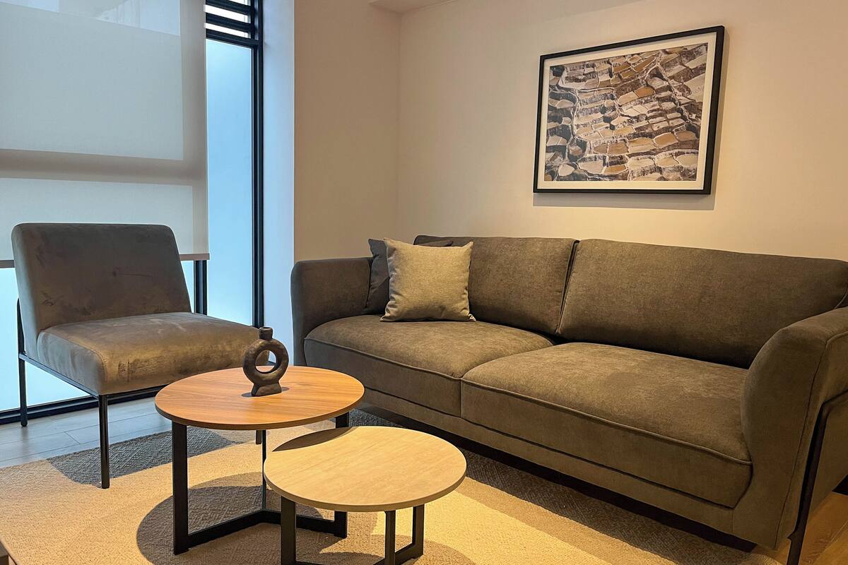 Ein modernes Wohnzimmer mit einer Couch, einem Sessel und einem kleinen Tisch.