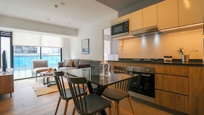 A modern kitchen with a dining area, wooden cabinets, and a large window providing a view of the city. - Arona by Wynwood House (Lima)