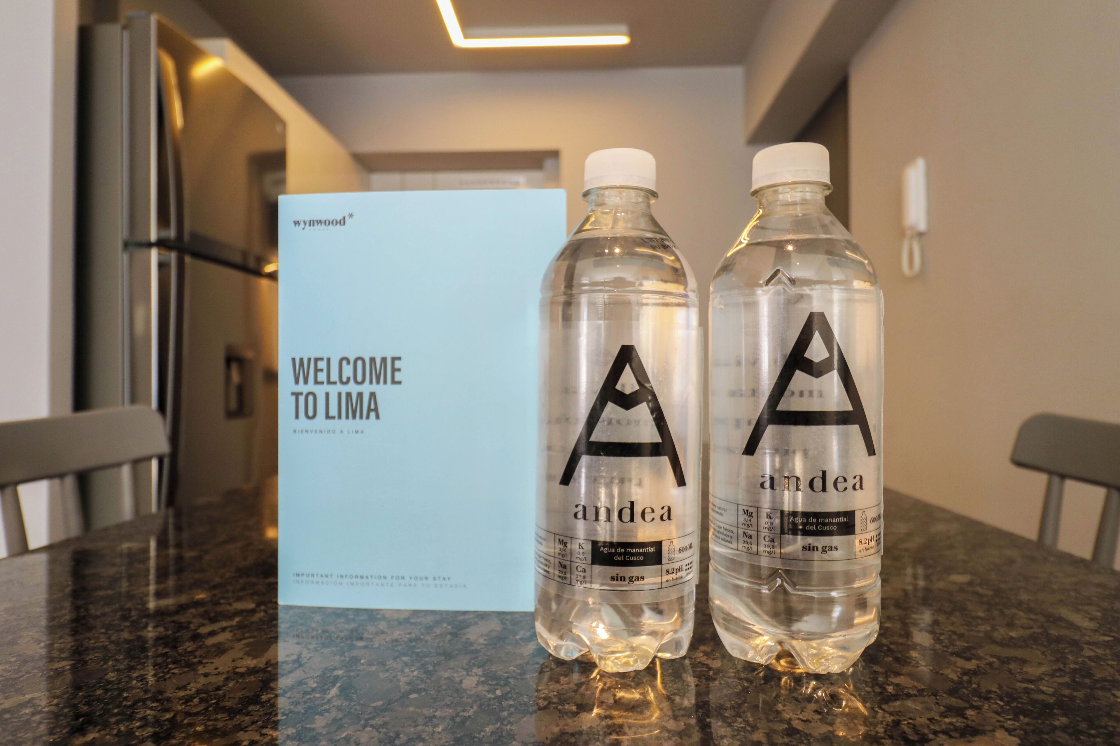 Two water bottles with labels on a countertop in a hotel room.