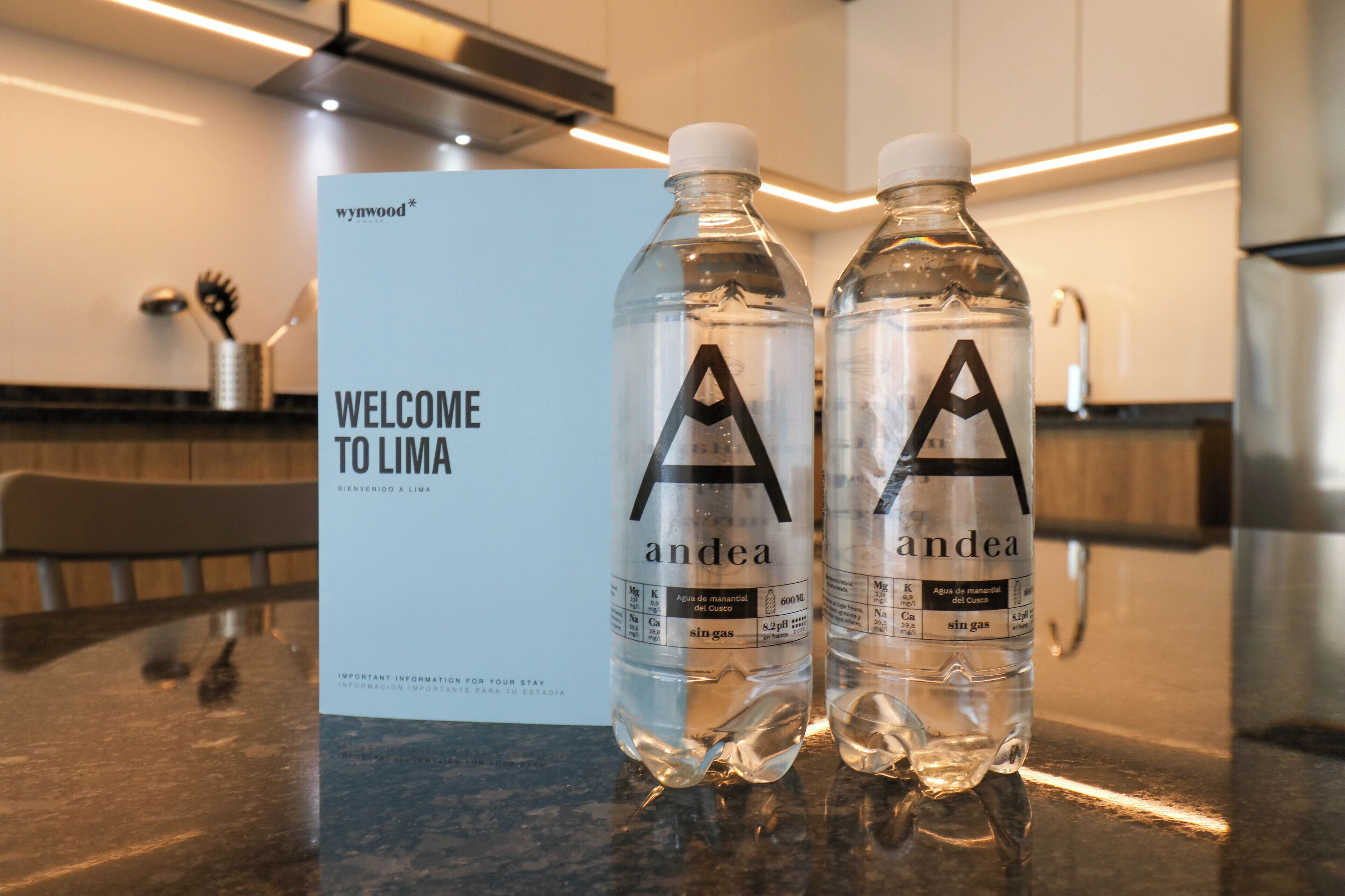 Two water bottles labeled 'andea' on a counter with a 'WELCOME TO LIMA' sign in the background.