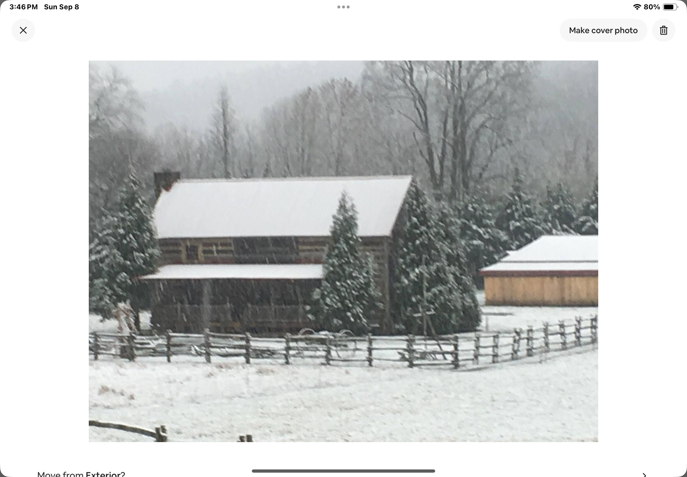 Un granero rústico con techo cubierto de nieve y una valla de madera en primer plano.