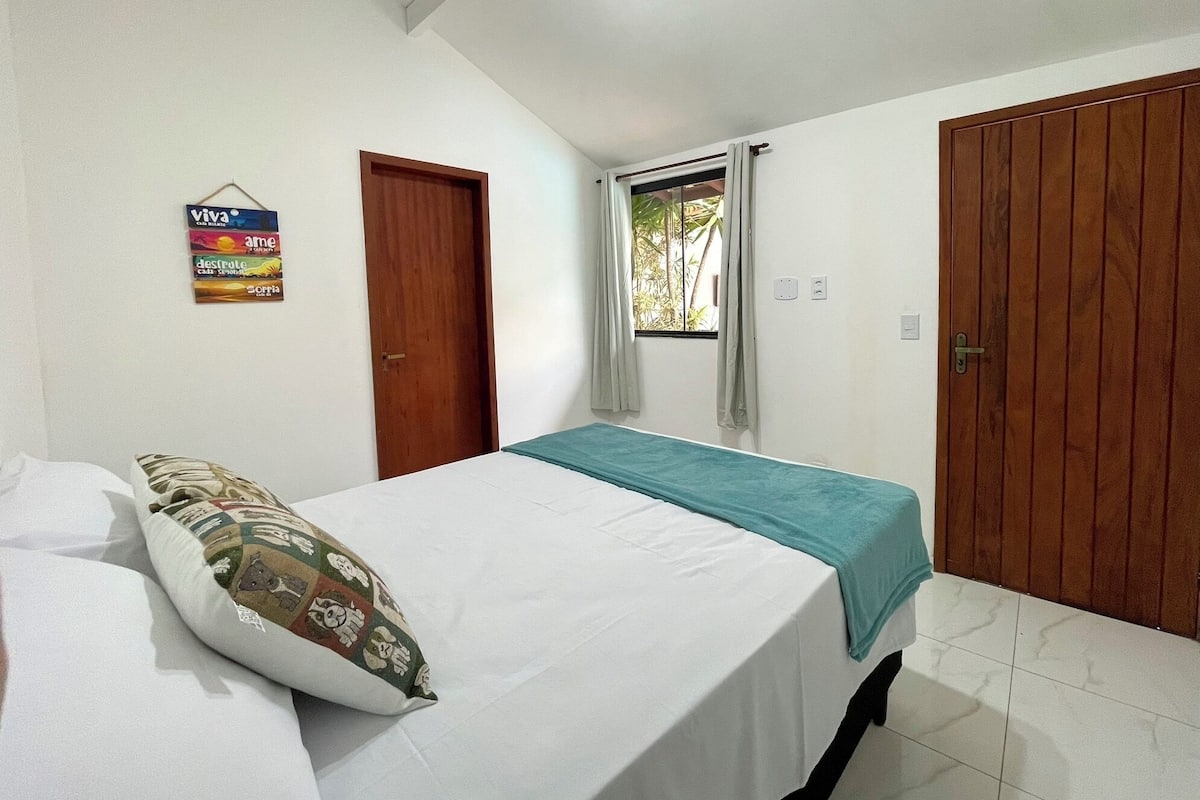 Un dormitorio con cama, ventana con cortinas, puerta de madera y una pared con un letrero.