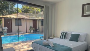 Una camera da letto con un ampio letto, vista su una piscina e un balcone.