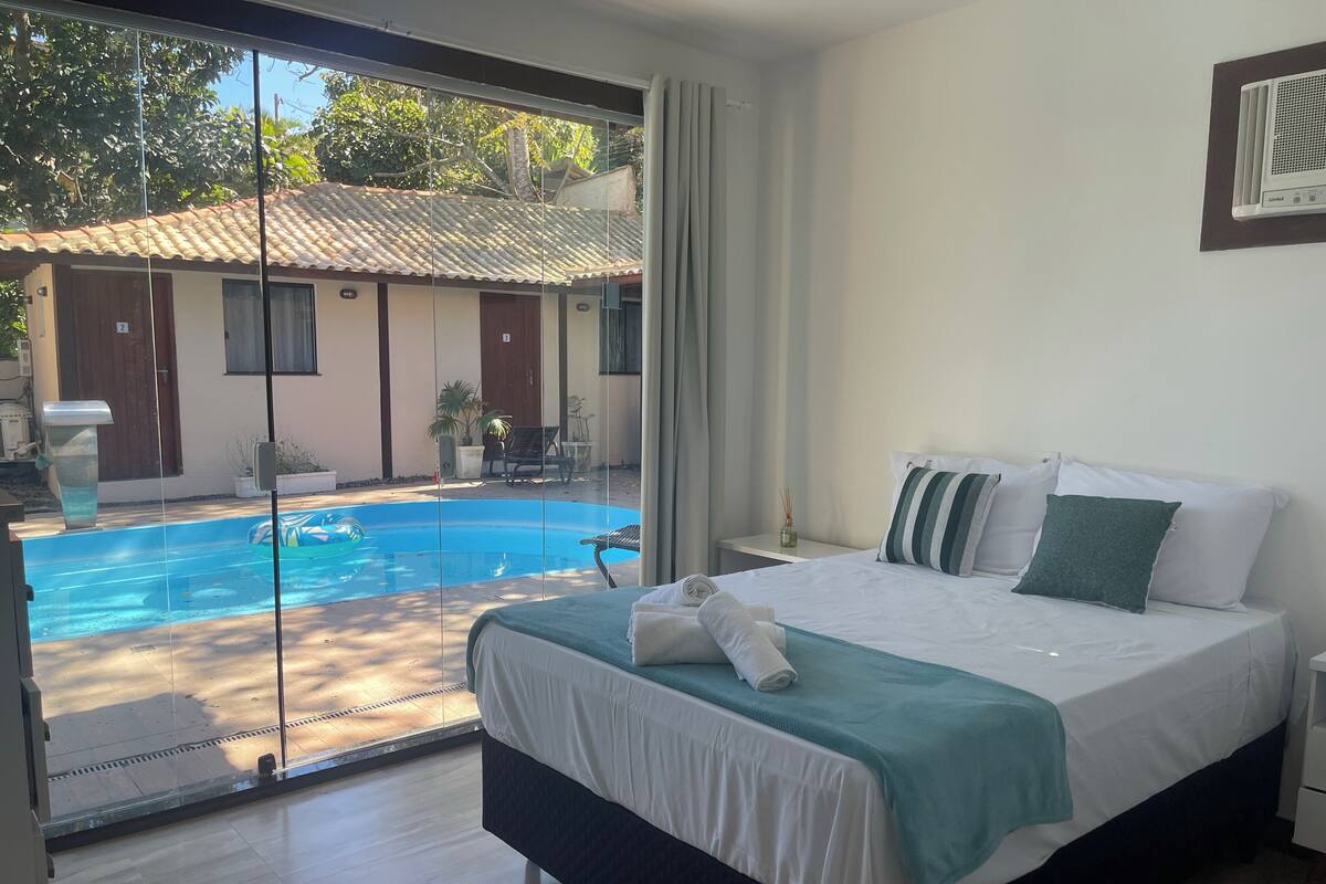 Un dormitorio con una cama grande, vistas a una piscina y un balcón.