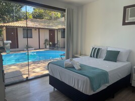 Un dormitorio con una cama grande, vistas a una piscina y un balcón.