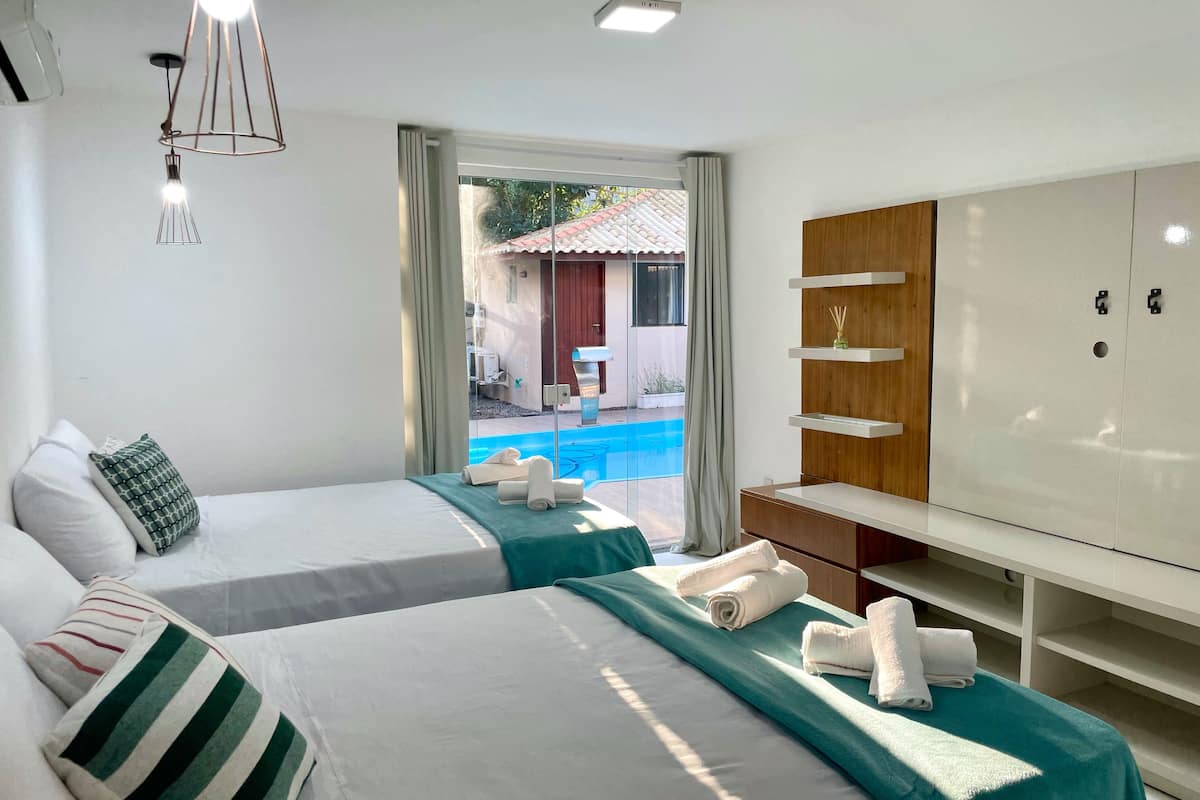 Habitación de hotel con dos camas, un armario grande y vistas a una piscina al aire libre.