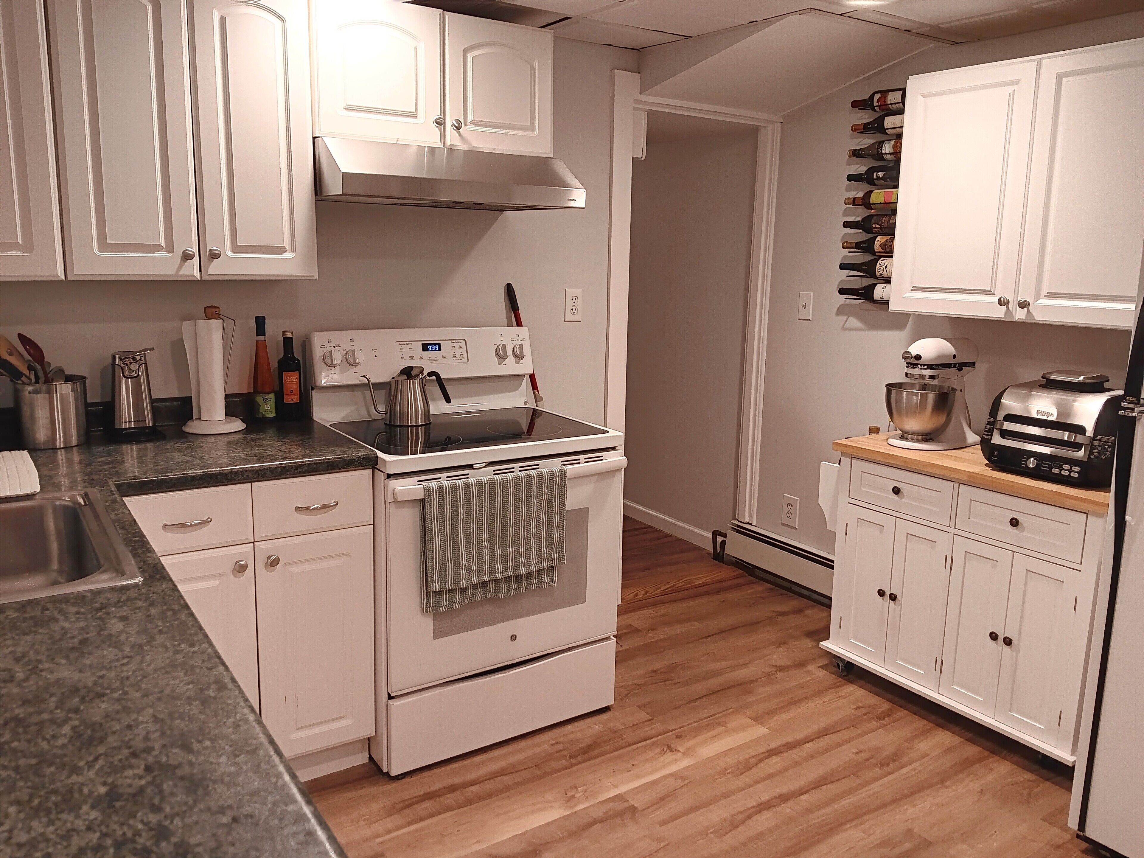 A kitchen with white cabinets, a stove, a mixer, and a toaster.