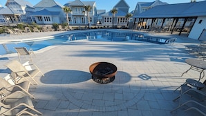 Un espace piscine avec des chaises longues et un foyer extérieur.