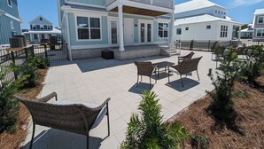 Une maison à deux étages dotée d’un patio couvert aménagé avec des meubles en osier.