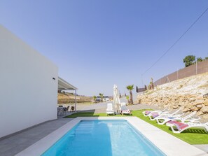 Piscina com espreguiçadeiras e área de estar coberta.