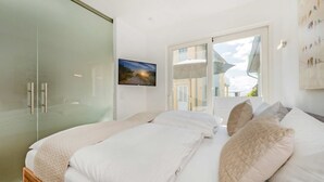 A bedroom with a bed, pillows, a painting, and a wardrobe. - "Kuschelnest" Vacation Home: Modernly Furnished with a Sun Terrace - Cozy (Kamminke)